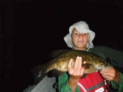 Leandro in a boat and holding up a bass