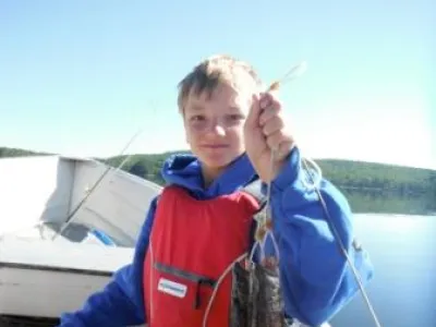 Leandro in a boat holding up two lake trout