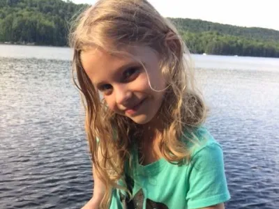 Sophia standing on the dock with a big smile on her face and holding a fish