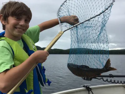 Julian holding up a net with a fish inside while standing on a boat
