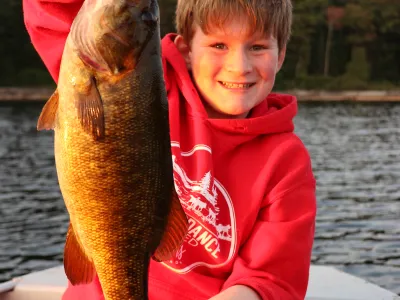 Cohen Elson holds up a small mouth bass while sitting on a boat in the middle of Percy Lake.