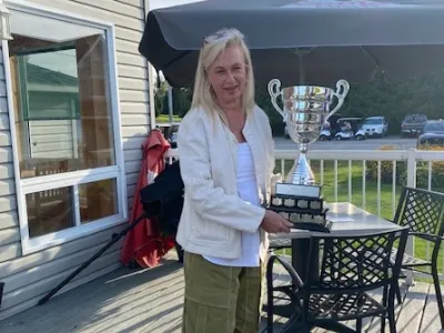 A woman presents the PLRA golf tournament trophy.