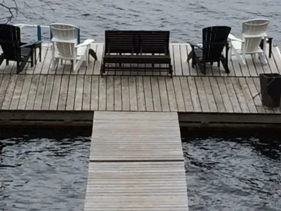 The ramp leading to a wide dock section with Muskoka chairs