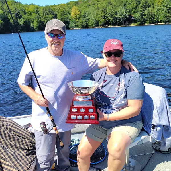 Mark and Jody Ristow in their fishing boat with the Percy Lake Bass Fishing trophy.