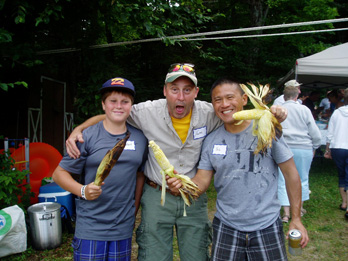 Three men making silly faces holding corn on the cob