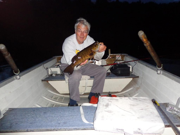 Jim sitting in a boat and holding a fish