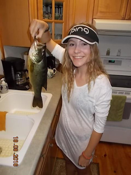 Sophia holding a fish above a kitchen sink