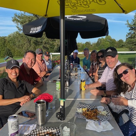 A group of golfers toast at a patio table after the tournament.