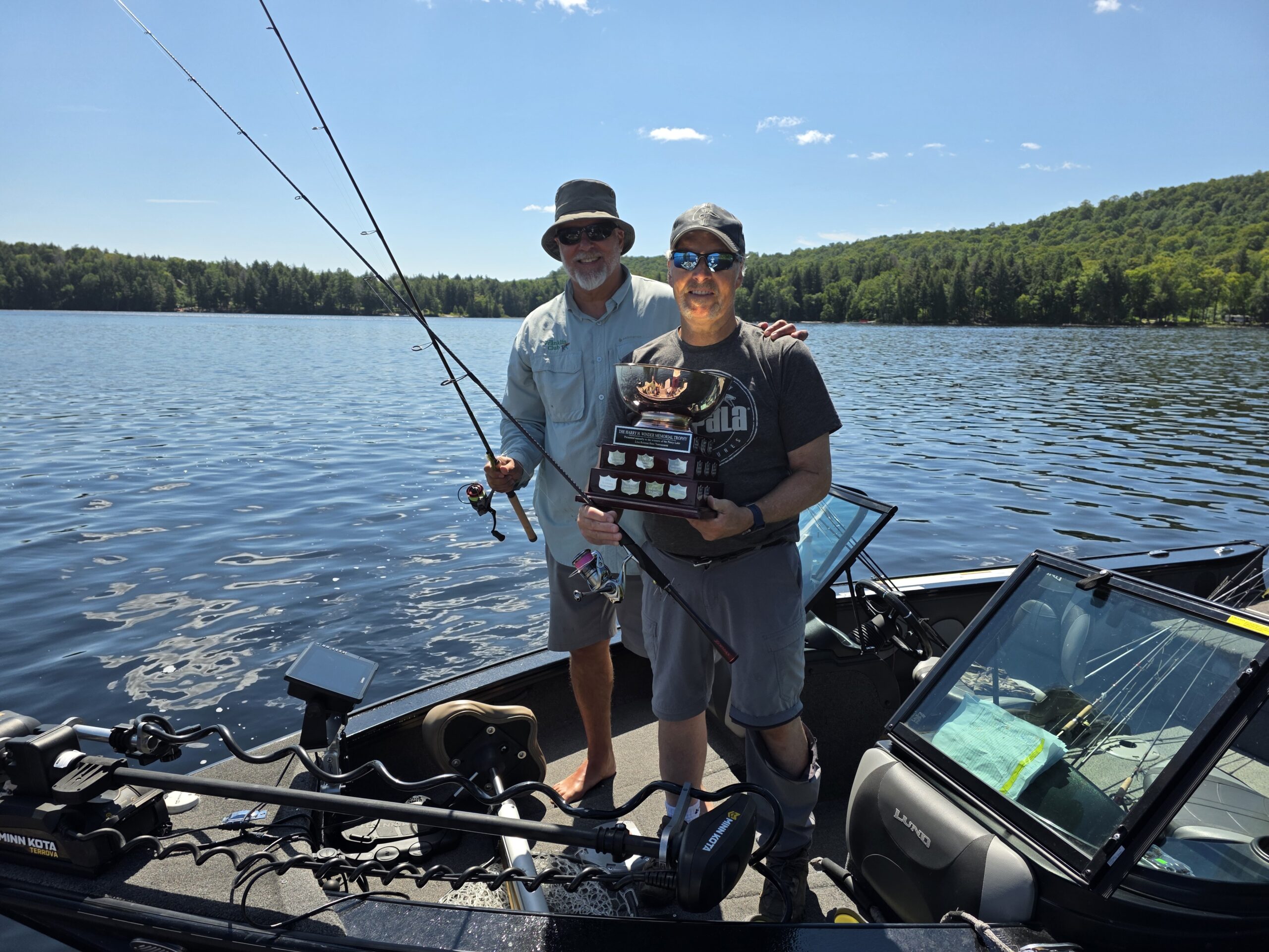 Mark Ristow and Lou Kiriakou pose with a fishing trophy while standing in a boat.