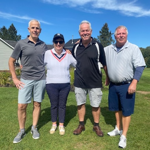 A team of four golfers, one woman and three men.
